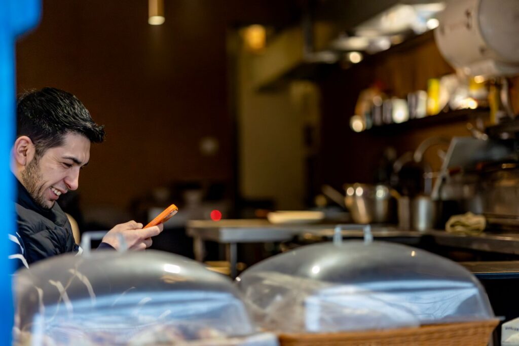 Smilende mand kigger på sin telefon på en café